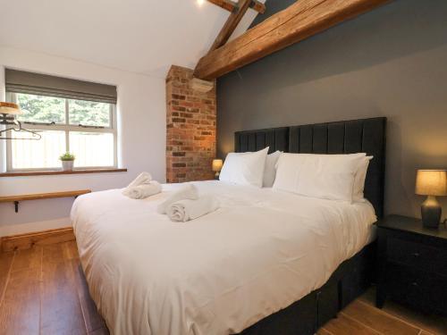 a bedroom with a large bed with white sheets at Molly's Cottage in Malton