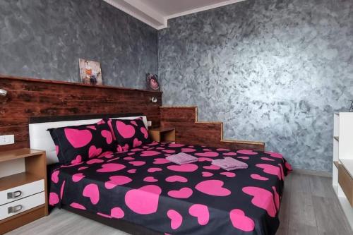 a bedroom with a black and pink bed with pink pillows at Ultracentral Residence 6 in Ploieşti