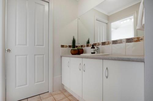 a white bathroom with a sink and a mirror at Adelaide Hills 4 bed home near Hahndorf Mt Barker in Nairne