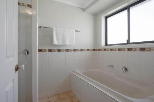 a white bathroom with a tub and a window at Adelaide Hills 4 bed home near Hahndorf Mt Barker in Nairne