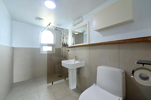 a bathroom with a white toilet and a sink at Sweet Stay Pension in Seogwipo