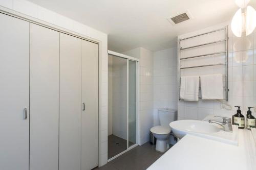 a white bathroom with a sink and a toilet at 1 Bedroom Apt with Parking Pool and Gym in Sydney