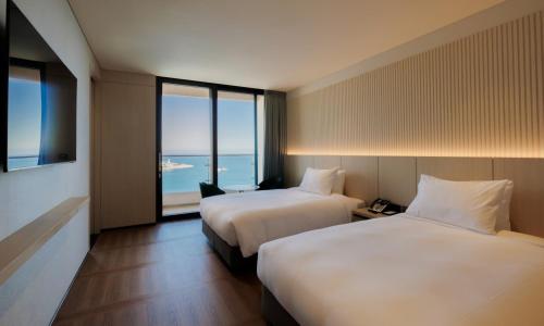 a hotel room with two beds and a view of the ocean at Ulsan Tanibay Hotel & Wedding in Ulsan