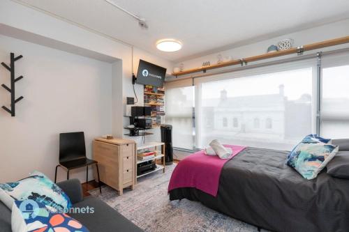 a bedroom with a bed and a large window at Studio Gem With Rooftop Space Prime Location in Sydney