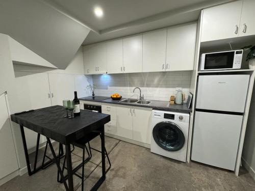 a kitchen with a black table and a white refrigerator at New Listing Loft Apt & A C in Heart of Devonport in Devonport