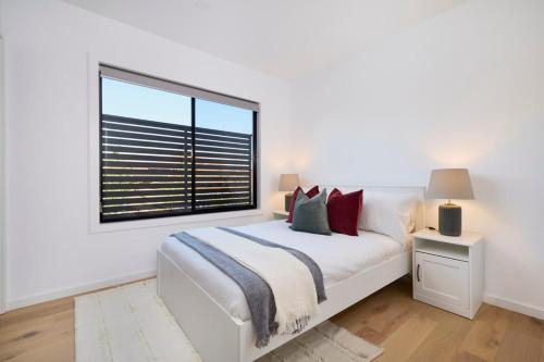 Habitación blanca con cama y ventana en 5 Bedroom 5 Bathroom Townhouse with Aircon, en Melbourne