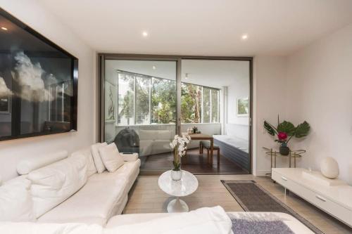 Una sala de estar con un sofá blanco y una mesa. en Luxurious Spacious OneBed Apt close to Bondi Beach, en Sídney