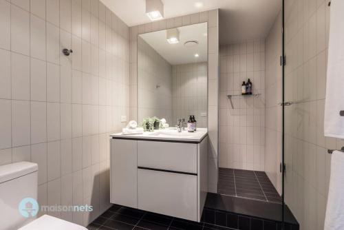 y baño blanco con lavabo y ducha. en Modern 2 Bdrm Apt with Water Views 2x Car Spots en Canberra
