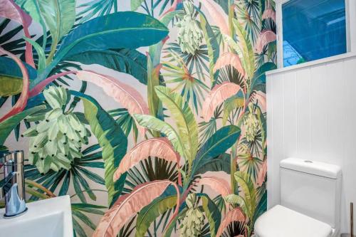 Gold Coast-Miami Mid-Century Beach Home With Pool في غولد كوست: حمام مع ورق جدران استوائي مع مرحاض
