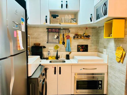 Elle comprend une petite cuisine avec des placards blancs et un réfrigérateur. dans l'établissement Cantinho do Aconchego DF, à Brasilia