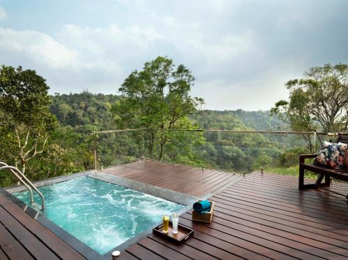 a pool on a deck with a view of the forest at Blanket Days Resort and Spa in Thekkady