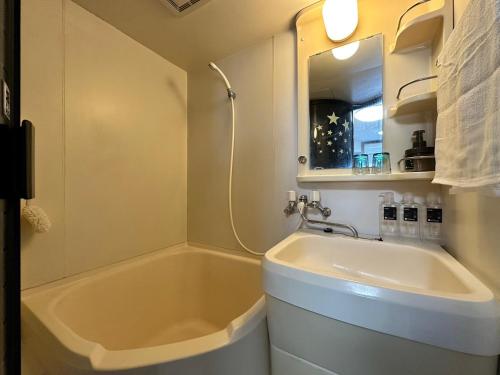 een badkamer met een bad, een wastafel en een spiegel bij ラ・パルフェド・札幌607/La Parfait Sapporo　607 in Kita-rokujō