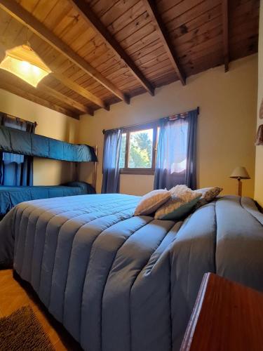 a bedroom with a large bed with blue sheets and a window at Posada del Ñireco in San Carlos de Bariloche