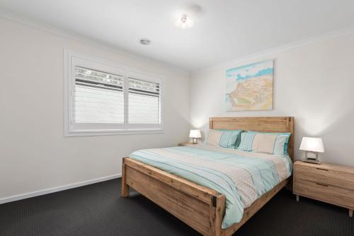 a bedroom with a wooden bed and a window at Getaway on the Rise in Portarlington