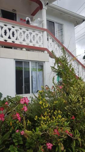 a white house with flowers in front of it at Rohan and Shelly's Inn in Castries