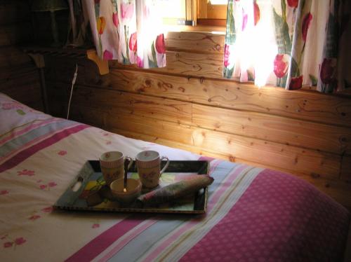 ein Tablett mit Essen und zwei Tassen auf einem Bett in der Unterkunft Residences Du Golf Des Roucous in Sauveterre