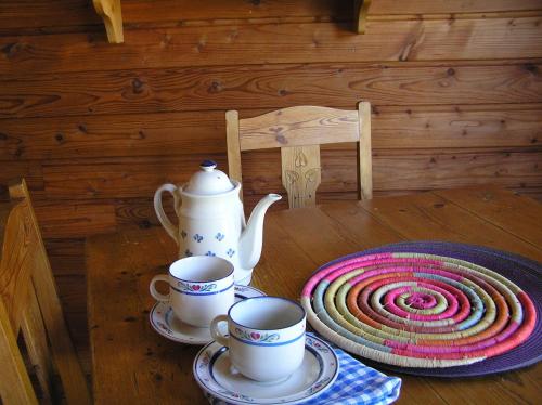 einem Holztisch mit zwei Tassen und einer Teekanne in der Unterkunft Residences Du Golf Des Roucous in Sauveterre