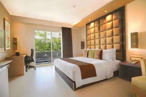 a bedroom with a large bed with a desk and a window at Eastparc Hotel Yogyakarta in Yogyakarta