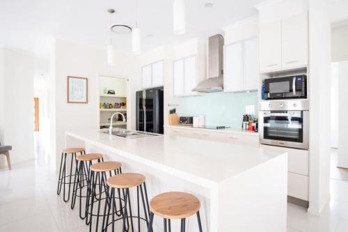 a kitchen with a white counter top and stools at Golden Beach Family Home with Pool in Golden Beach