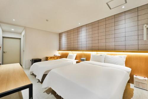 two beds in a hotel room with white sheets at Ciel mini hotel in Gyeongju