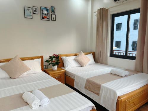 two beds in a room with a window at GOLDEN LAND HOTEL in Cat Ba