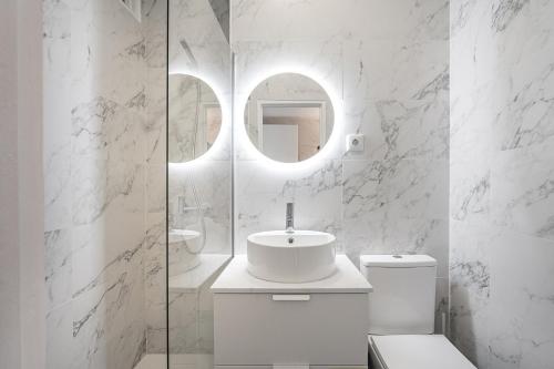 een witte badkamer met een wastafel en een spiegel bij GuestReady - A sunny moment in Porto in Porto