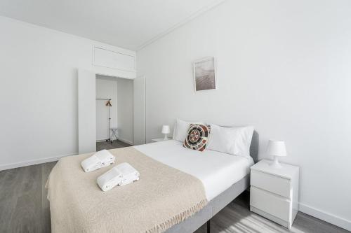 ein weißes Schlafzimmer mit einem Bett und einem Nachttisch in der Unterkunft GuestReady - A sunny moment in Porto in Porto
