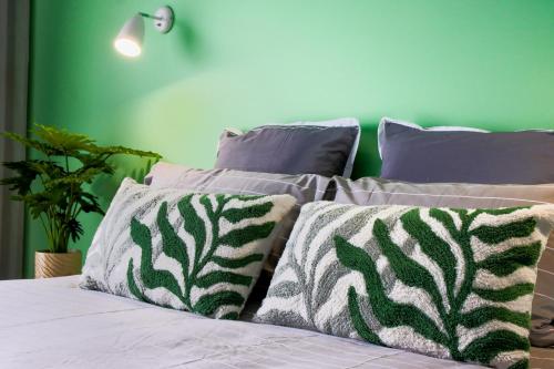 a bed with three pillows and a green wall at 239 High by Regional Escapes in Geelong