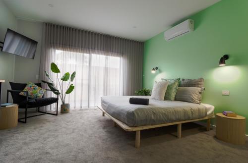 a bedroom with green walls and a bed and a chair at 239 High by Regional Escapes in Geelong