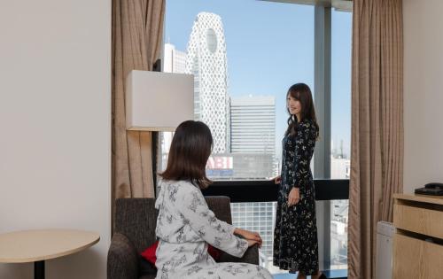 two women in a hotel room looking out the window at JR Kyushu Hotel Blossom Shinjuku in Tokyo