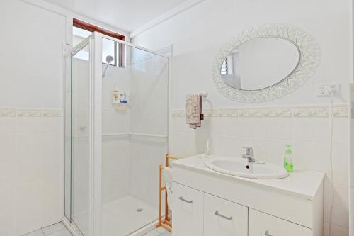 a white bathroom with a shower and a sink at Jacaranda Cottage at the Beach in Cowes