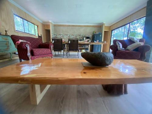 una sala de estar con una mesa de madera con un tazón. en Hospedaje acceso a laguna y tinaja, en Quillón