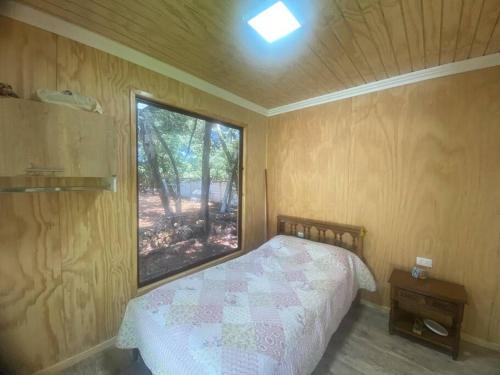 a small bedroom with a bed and a window at Hospedaje acceso a laguna y tinaja in Quillón