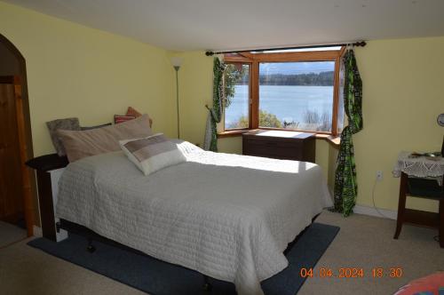 um quarto com uma cama branca e uma janela em Estuary House Reflexology B&B em Courtenay