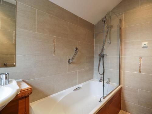 a bathroom with a bath tub and a sink at Craggs Cottage in Smailholm