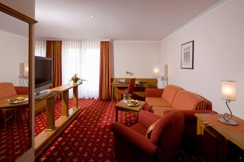 a hotel room with a couch and a television at Germanenhof in Sandebeck