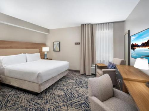 Cette chambre comprend un lit, un bureau et une chaise. dans l'établissement Candlewood Suites Champaign-Urbana University Area, an IHG Hotel, à Champaign