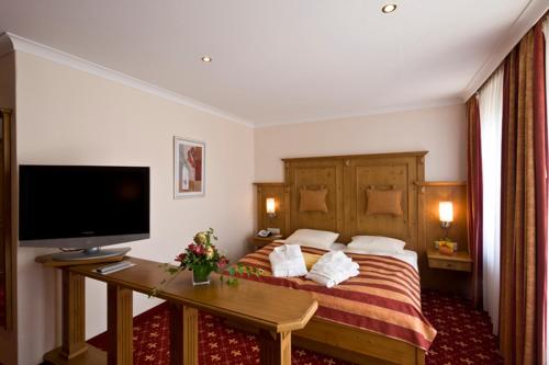 a hotel room with a bed and a desk with a television at Germanenhof in Sandebeck