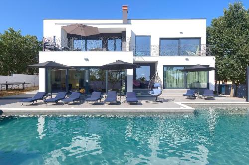 een huis met een zwembad met stoelen en parasols bij Ferienhaus für 10 Personen in Loborika, Istrien Südküste von Istrien in Loborika