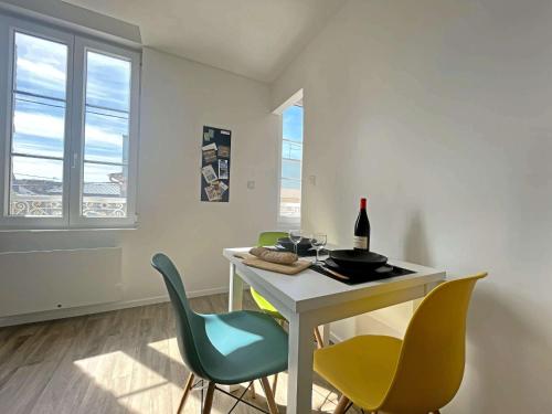 Cette chambre comprend une table avec des chaises et une bouteille de vin. dans l'établissement Charmant T2 rénové à Berck Plage, proche mer et centre, idéal pour séjour sur la côte d'Opale - FR-1-646-61, à Berck-sur-Mer