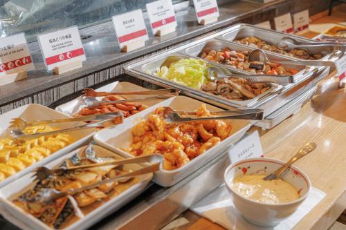 a buffet filled with different types of food in trays at JR Kyushu Hotel Blossom Shinjuku in Tokyo
