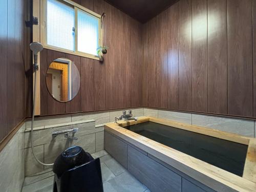 a bathroom with a large bath tub with a mirror at Koguma no ie in Nozawa Onsen