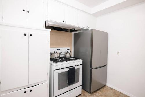 a kitchen with white cabinets and a stainless steel refrigerator at ModernHaven -SoFi, Forum, Intuit in Hawthorne