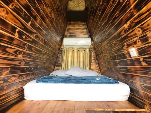 a bed in a room with a wooden wall at Pousada e sítio do Robinho in Timbe do Sul
