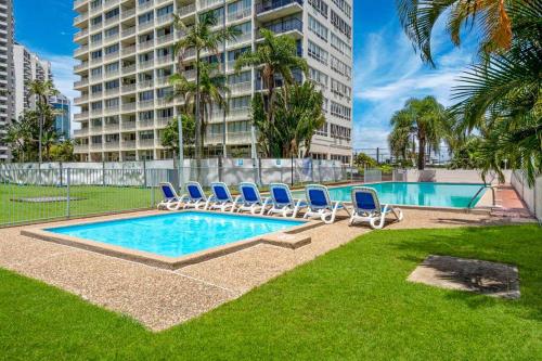 a swimming pool with lounge chairs and a building at Condor Surfers - Hosted by Coastal Letting Company in Gold Coast