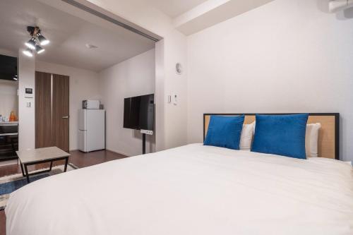 a bedroom with a large white bed with blue pillows at Art Nagara in Osaka
