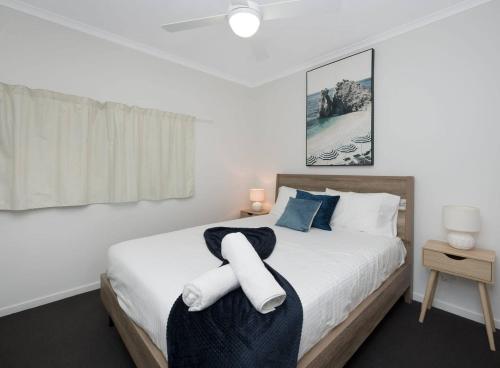 ein Schlafzimmer mit einem großen weißen Bett mit blauen Kissen in der Unterkunft Stunning 2BR Beachfront Retreat in North Ward