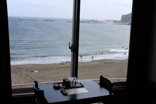 a view of a beach from a window with a table and chairs at Hotel Shiosai in Fujisawa