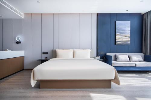 ein Schlafzimmer mit einem großen weißen Bett und einem Sofa in der Unterkunft Atour Hotel Jinan Huashan Huanyu Max in Jinan