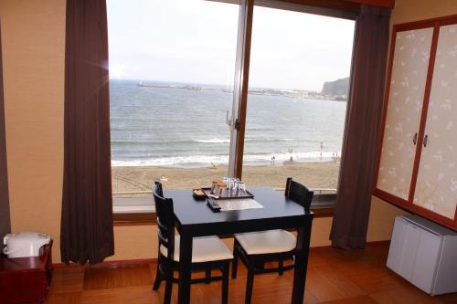 a dining room with a table and a view of the beach at Hotel Shiosai in Fujisawa